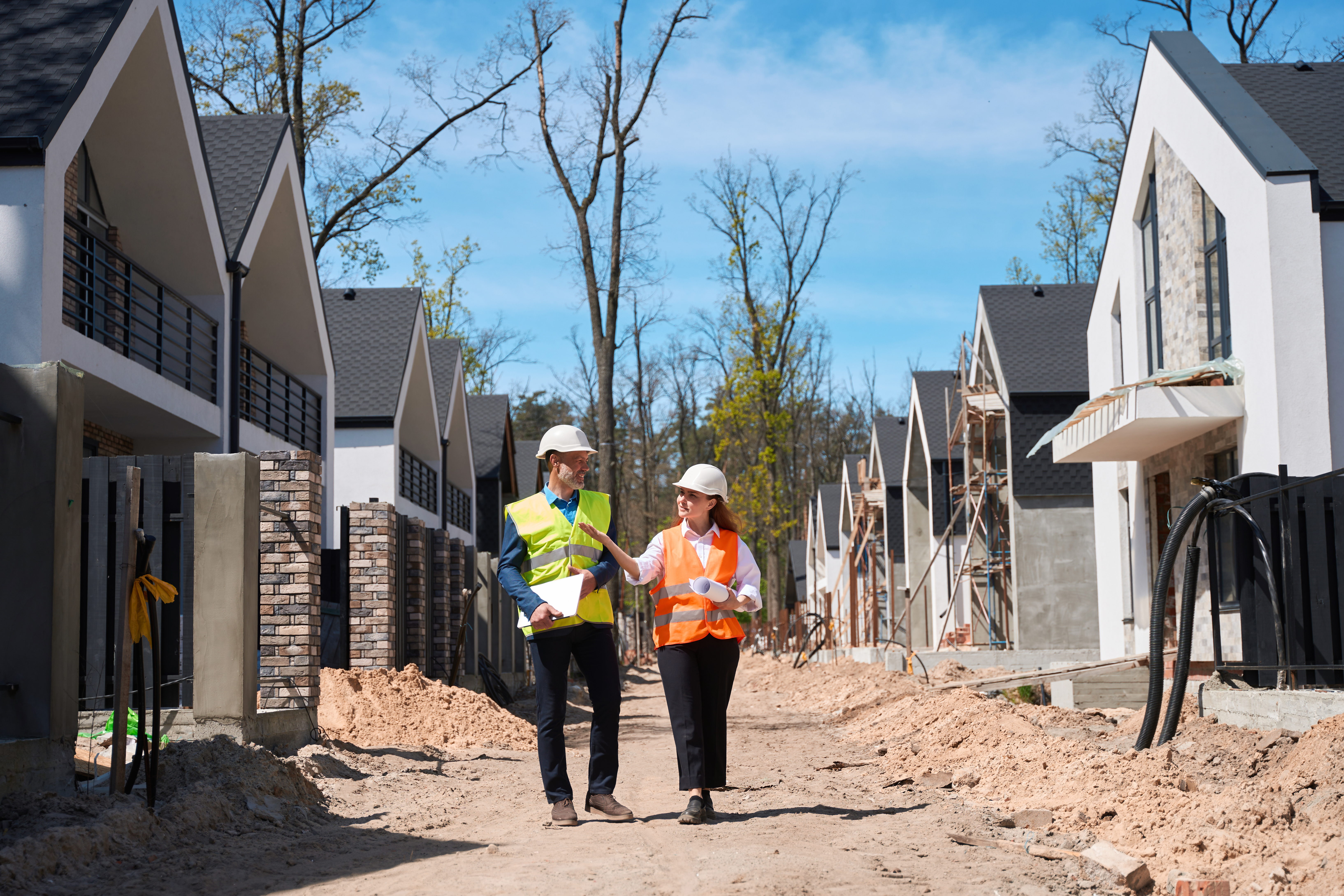 Forewoman in hardhat talking to inspector walking along construction site